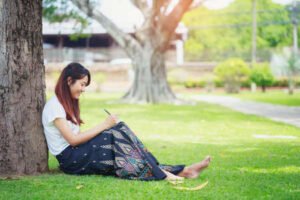 84635859 mujer joven sentada bajo un gran arbol y escribir su diario mujeres con concepcion natural