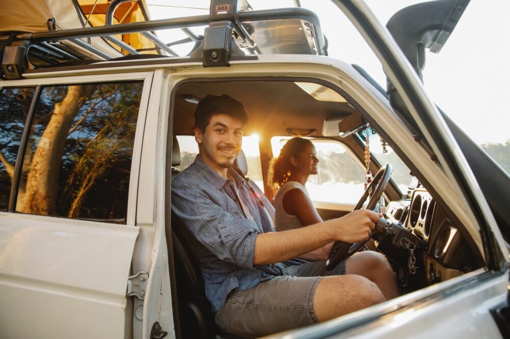 cheerful young diverse couple couple traveling by car at sunset